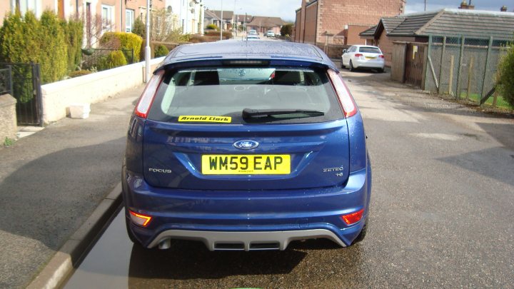 Currys Aint Corsa Pistonheads Wait - In the image, we see a bright blue Hyundai hatchback parked on a gray street. The license plate of the car reads WMS59 EAP. There are other houses visible in the background, suggesting a residential area. The sky looks overcast, casting a soft light on the scene. A regular car is also parked further down the street, adding to the everyday street scene.