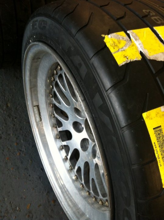 A close up of a car parked on a street - Pistonheads - The image shows a close-up of a tire on a vehicle with a focus on the rim. The tire appears to be a spare tire, indicated by the word "spare" visible on the sidewall. The rim itself has a distinctive metal spoke wheel design. The tire is mounted on the wheel, and the tread on the tires looks to be of a medium depth pattern. The overall condition of the tire and wheel suggests it might be used, especially given the visible markings on the sidewall.