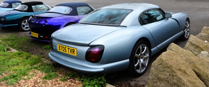 TVRCC Burghley Horse Power - Saturday drives - Page 6 - TVR Events & Meetings - PistonHeads - The image presents a parking lot scene featuring a group of sports cars. One of the cars is prominently positioned in the foreground with its hood raised, indicating some mechanical activity or repair. The cars have European-style license plates, and the background includes a grassy area suggesting a backdrop of greenery. There are no visible texts or distinctive markings within the image. The photograph has a naturalistic style, capturing the scene with realistic colors and details.