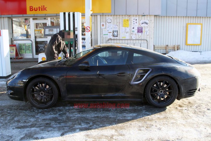 Pistonheads Shots Porches Turbo Upcoming Spy - In the image, a man is standing at a car fuel pump, presumably refueling his black Porsche. The car is sleek and expensive, idling patiently at the pump. The setting is a gas station with a store visible in the background. Notably, a "no smoking" sign is affixed to the fuel pump, indicating the gas station's policies on smoking at the pumps. The overall atmosphere of the picture suggests a regular day at a gas station.