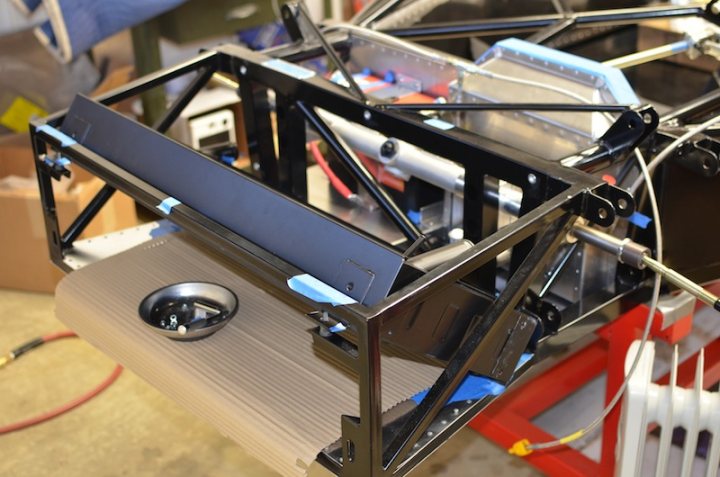 A desk with a keyboard and mouse on it - Pistonheads - The image depicts a robust assembly of a wooden frame and a metal frame, possibly for a piece of exercise equipment. Several hoses and wires are visible, suggesting complexity in the structure's functionality. Within the assembly, various springs are sandwiched between the wooden and metal frames, adding to the intricate design. The equipment's parts are arranged in an organized manner, highlighting the precision involved in constructing the device.