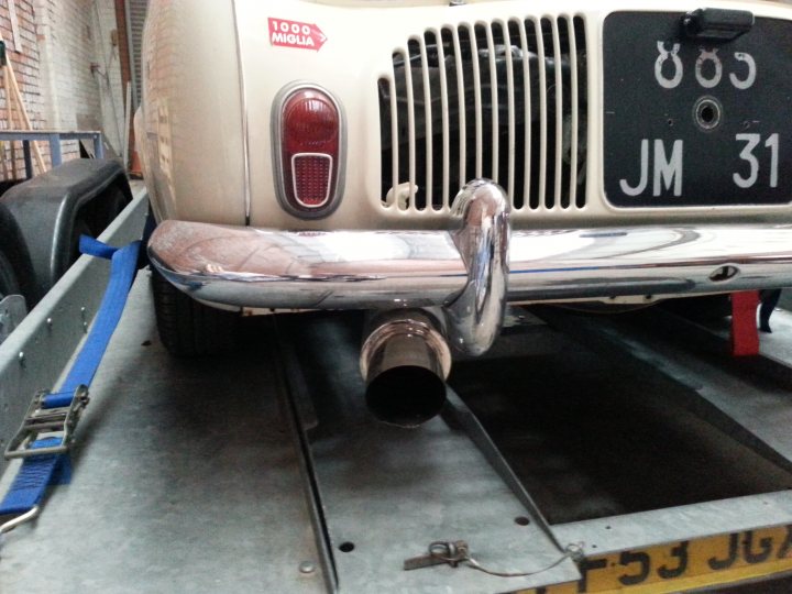 A car that is sitting in the street - Pistonheads - The image shows a vintage car on a lift, possibly in a maintenance workshop. The car's bumper is lifted and held in place by a blue strap. The license plate is prominently displayed on the front of the vehicle. The car is an older model, as indicated by the chrome grill and the overall vintage style. The lift features a platform with metal bars, providing support for the car during maintenance.