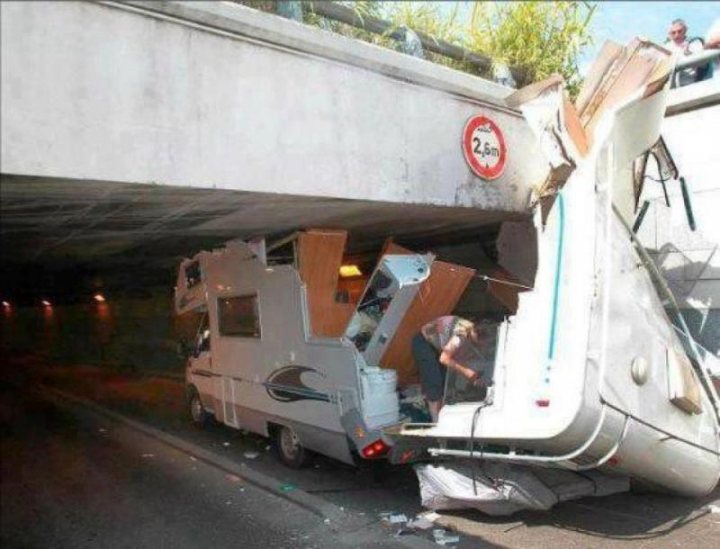 Is this forum out of season?  - Page 1 - Tents, Caravans & Motorhomes - PistonHeads - This image captures a scene from a road where a large RV or caravan is severely damaged and undergoing a rescue operation. The RV is on its side with a person standing near it, possibly assessing the situation or assisting in the rescue effort. The context is a highway, and in the backdrop, there is a concrete overpass structure and a sign reading "2.50." The debris surrounding the RV suggests a significant accident, and the image conveys a sense of urgency and attention.