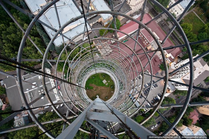 The Camera can capture some fantastic moments....II - Page 237 - Photography & Video - PistonHeads - The image captures a unique perspective from the top of a tall structure, which appears to be an observation tower or communication tower equipped with a safety railing. Beneath the railing, a rotating platform can be seen, possibly for tours or maintenance purposes. The vantage point offers a bird's-eye view of the surroundings, featuring a variety of buildings and a urban landscape. The structural framework of the tower is prominently visible, with elements of steel and concrete.