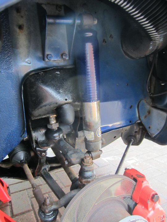 A motorcycle that is sitting on the ground - Pistonheads - The image is a close-up photo featuring mechanical components, likely taken from an automotive perspective, specifically concentrating on the undercarriage of a vehicle. There is a focus on a wooden plank bristling with blue nails, which is a striking contrast against the metallic hues of the vehicle parts. The perspective of the shot suggests it is panning over the components, emphasizing the details and textures of both the wood and the mechanical elements. The wooden plank runs horizontally across the bottom of the image, while the metal components fill the vertical space, providing a balanced composition.