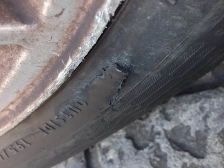 A pair of rusty scissors sitting on the ground - Pistonheads - The image showcases a close-up of a car tire, revealing its pattern. The tire's tread is intact, but closer inspection reveals a significant issue - gashes are visible on the side and base of the tire. These damages suggest the tire is old or has been exposed to rough road conditions.

The car itself is partially visible in the background, with its metallic components reflecting the surrounding light. The focus, however, remains on the tire's distressing condition, with the surroundings appearing somewhat dull and unremarkable compared to the evident tire woes.

There is a stark contrast between the tire's machined tread and the rock ledge it sits upon, emphasizing the close-up perspective and the ruggedness of the environment. Despite the assortment of damage, including a missing bolt that might concern a casual viewer, the tire continues to hold its ground, seemingly refusing to break or quit.