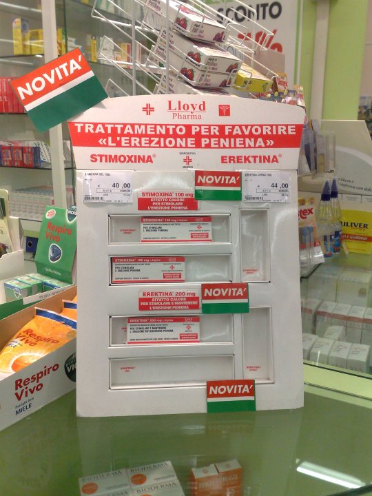 The image features a display of medical packages within a store setting, most likely a pharmacy. The packages are designed to explicitly state the medicine's purpose, such as "TRATTAGLIMPENTO PER FAVORE LERERIZIONE" which can be translated as "Treatment for heart failure due to pregnancy." The packaging is predominantly white, red, and green, with the brand "Novita" primarily printed on these packages. There is a three-row display, and the packages are arranged in a way that the front row is facing the camera. The price labels on the packages indicate the retail cost of the medications.