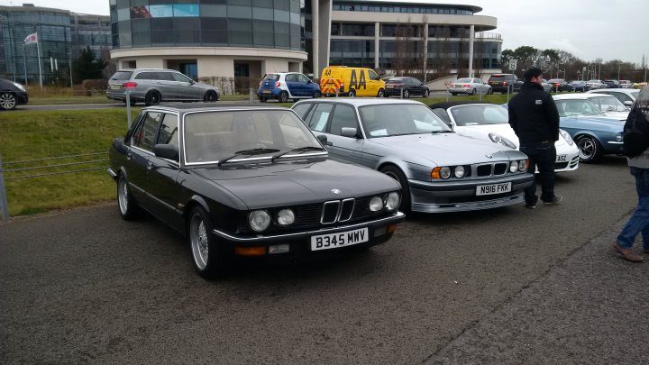 RE: Mercedes-Benz World Sunday Service 20/03 - Page 23 - Sunday Service - PistonHeads - The image shows a parking lot overflowing with vintage cars. Two Mercedes-Benz models, distinguished by their iconic rounded headlights, are parked closely together. The cars, one black and the other silver, are parked side by side in the foreground, while other cars of various colors and models fill the background. A person is visible in the lower right corner of the image, adding a sense of scale to the scene. The angle and perspective suggest that the image was taken from an elevated position.