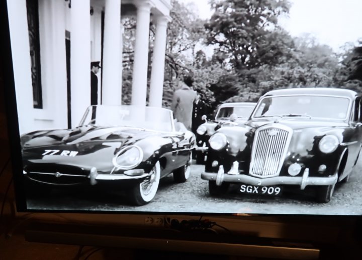 Pistonheads - The image shows a photograph of an older couple seated in vintage cars. The car on the left is a dark-colored convertible with the top down, and the one on the right appears to be a black classic sedan. They are parked side by side under an open sky. There is no visible text or branding in the image. The style of the cars suggests this photo was taken several decades ago, capturing a moment from the past that showcases classic automobiles and possibly the couple's hobby or interest in classic vehicles.