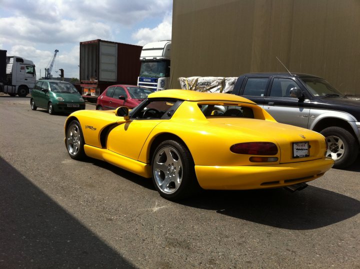 Wait Worth Pistonheads Long - The image showcases a vibrant yellow sports car parked in an industrial lot with various vehicles. The setting exudes a sense of the imbibed craftsmanship that went into creating this vehicle's exterior. The yellow sports car is positioned in the foreground, drawing the viewer's attention with its sleek aerodynamics and contemporary design.