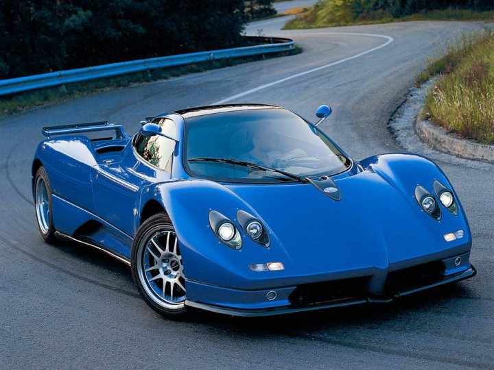 Your favourite car from the year you were born in... - Page 12 - General Gassing - PistonHeads - The image showcases a vivid blue race car in action on a winding road with a blue guardrail. The car has distinctive open cockpit, hinting at its speed capabilities. It's built with sleek aerodynamics, and the craftsmanship is evident in the streamlined design and the intricate details of the wheels.