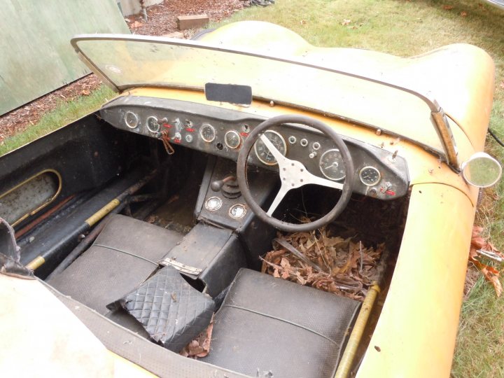 A close up of a motorcycle parked in a parking lot - Pistonheads - The image features an old, likely vintage, vehicle with an interior visible. The dashboard is made up of several gauges and switches, typical of antique cars. A steering wheel is in the center of the dashboard, and a clutch is visible. The car appears to be open for viewing, possibly in a private collection or on display at an automotive show or museum. Additionally, the interior of the vehicle is in a state of disrepair, visible springs and mechanisms can be seen. It is parked on grass, indicative of an outdoor exhibition or storage location.