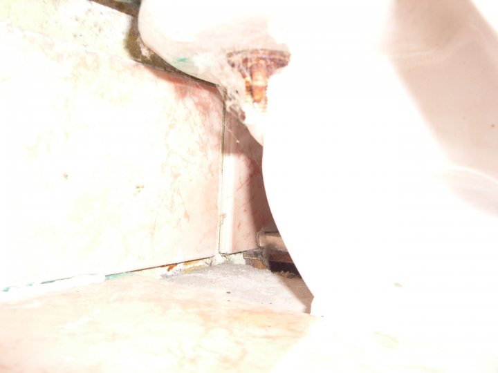 Broke Pistonheads Handle Morning Toilet - This image shows a close-up view of a bathroom floor with tiles that exhibit a worn and aged appearance. The tiles have accumulated dirt and grime over time, revealing areas of lifting grout and possible water damage. In the foreground, there is a piece of debris on the floor, suggesting that the floor needs cleaning. The lighting in the photograph casts a stark shadow, emphasizing the texture of the tiles and the contrast between the light and dark areas.