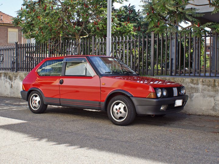 Your favourite car from the year you were born in... - Page 12 - General Gassing - PistonHeads - In the image, there's a unique car parked on the side of a road. The car is a striking combination of white and yellow with a black stripe that extends along the sides. The car has two doors, which suggests it's a compact or hatchback model. 

The car is positioned in front of a metal fence, adding a sense of depth to the image. There is trees visible in the background, indicating that this scene might be taking place in a suburban or rural area. 

The car and the surroundings together create a scene that seems to be out of an ordinary day, perhaps indicating that the car is unique or that it's parked in an unusual location.