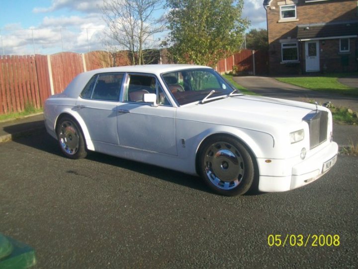 Badly modified cars thread - Page 224 - General Gassing - PistonHeads - The image depicts a single, old-style Bentley car parked on a paved driveway next to a wooden fence. The car's design, characterized by a prominent grille, round headlights, and white paint, is reminiscent of era styles. The car is well-maintained, suggesting it's a cherished luxury vehicle. The timestamp in the image indicates it was taken on May 3, 2008. The surrounding environment features a house with a lawn in the background, providing a residential setting.