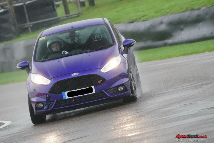 Fiesta ST MK7.5 Track car  - Page 19 - Readers' Cars - PistonHeads - The image captures a dynamic scene on a racetrack. A blue car, possibly a Ford Mustang given its distinctive shape and size, is in motion. The driver, visible through the window, is actively engaged with the wheel, navigating the track under what appears to be rainy conditions, as suggested by the wet road surface and droplets on the windshield.

The car is traveling at a high speed, indicated by the blurred background that suggests motion. The racetrack is lined with what seems to be guardrails and other safety barriers, emphasizing the competitive nature of the setting. The overall atmosphere of the image conveys the thrill and intensity of motorsport.