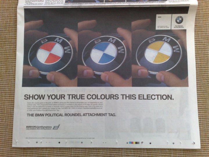 Spotting Pistonheads April Fool - The image displays a newspaper folded and opened to reveal a series of photographs on the front cover, focusing on BMW car wheels. The language of the text is German, and the newspaper features an advertisement for the BMW political foundation. The text encourages readers to show their true colors and join the BMW political circle by attaching a tag to the newspaper.