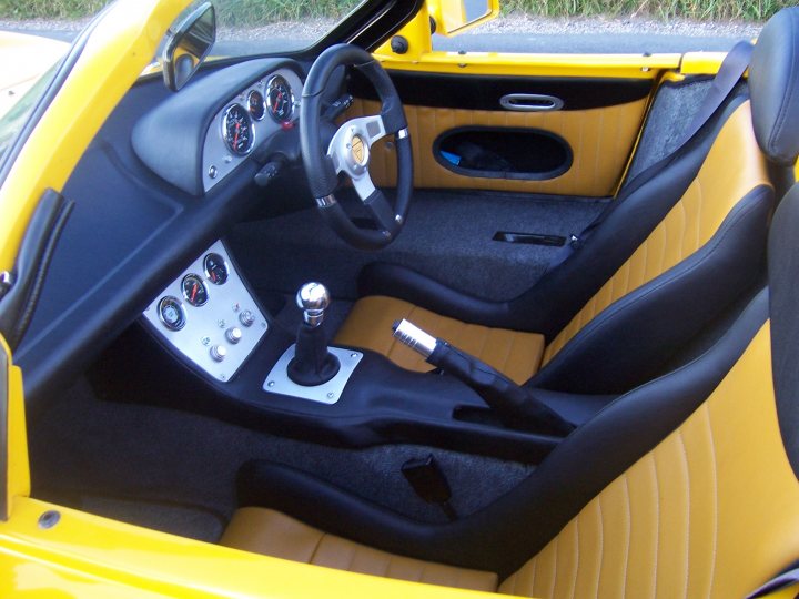 G26 better than G33 ... ? - Page 1 - Ginetta - PistonHeads - This image showcases the interior of a convertible car, which is painted in striking contrasts of black and yellow. The car is equipped with a manual transmission, and the steering wheel displays a collection of instrument gauges and control buttons. The driver's seat is positioned to the right, and the dashboard and door panel are distinctly visible, imparting a sense of luxury and performance.