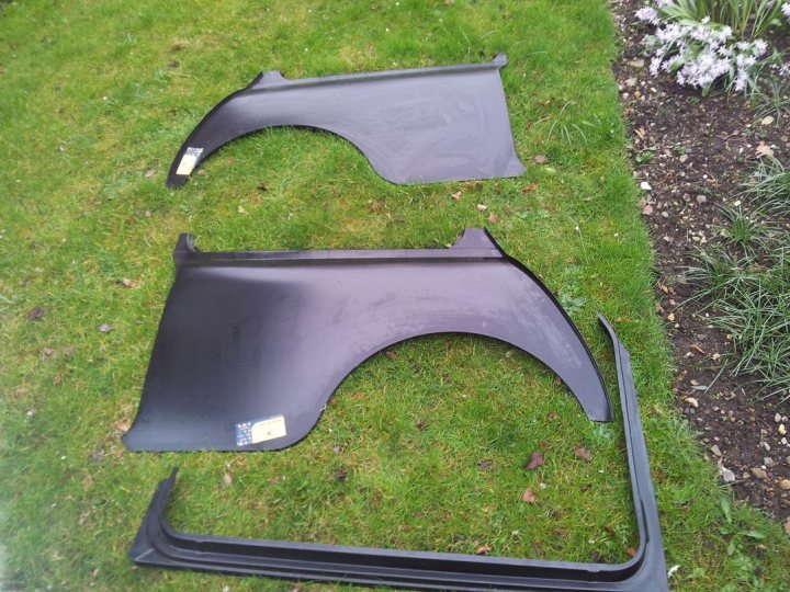 Pistonheads - The image shows two black car bumpers or front end fascias laid out on a grassy lawn with their backs facing the viewer. They appear to be in use, with the spots where the car's metal contacts would be visible from the back. There's some dirt scattered around on the grass, indicating an outdoor setting. The photo seems to be taken from a higher angle, possibly taken out of a car, given the somewhat contextual throw-in. In the right side of the photo, there's a small garden bed with some flowers, adding a bit of color to the scene.