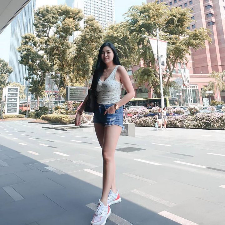 A woman in a short skirt standing on a sidewalk