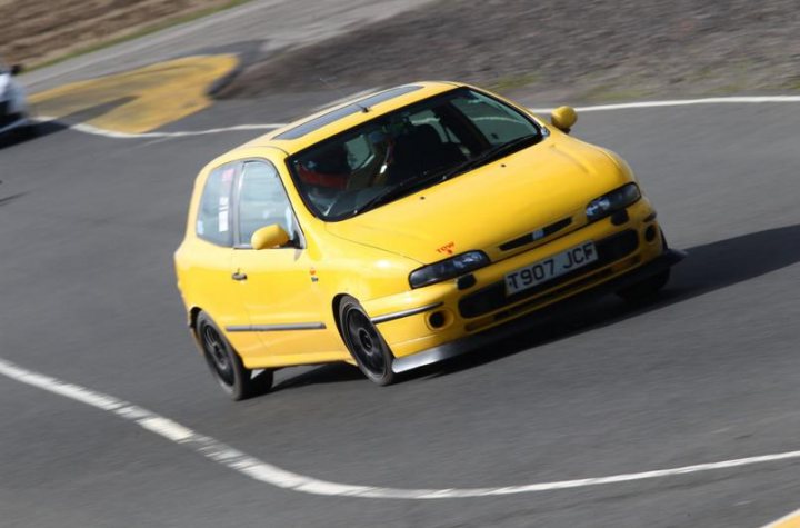 A yellow car is parked on the side of the road - Pistonheads