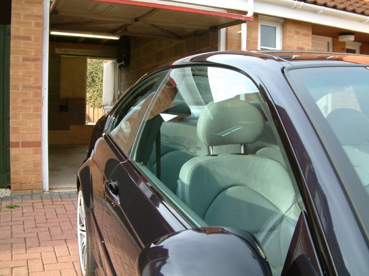 Lucky Detailed Luciano Pistonheads Motor - In the image, there is a black car parked in a brick driveway. The car is facing the camera, and its sunroof is open. The interior of the car appears to be taupe or light beige in color, and the car looks modern with sleek curves. The setting seems to be residential, as indicated by the brick wall and the woodgrain side of the house in the background. The driveway is quite long and wide, providing a spacious parking area.