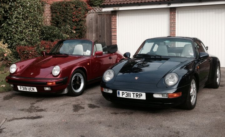 Pictures of your classic Porsches, past, present and future - Page 3 - Porsche Classics - PistonHeads - The image presents a tranquil scene on a street corner with two classic sports cars parked side by side in front of a house. The car on the left is painted a vibrant red, while its counterpart on the right glistens in a glossy black finish. Each car is adorned with a white license plate that clearly reads "F51 UCR". The house behind the cars is well-maintained, with a welcoming brick wall that adds a touch of warmth to the scene. The cars and the house together create a picturesque setting of two classic sports cars at rest on a sunny day.