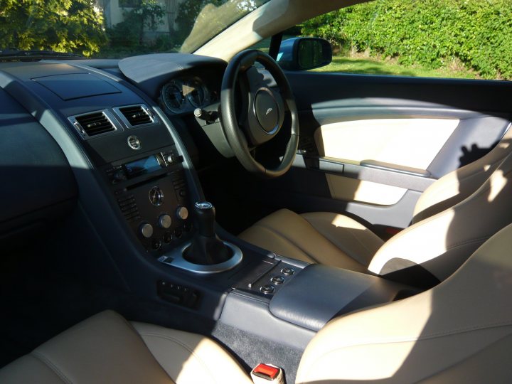 Ish Newbie Pistonheads - The image depicts the interior of a vehicle, specifically the driver's seat and part of the passenger seat. The steering wheel is on the left side of the image, indicating the vehicle is likely designed for right-hand drivers. There are multiple control dials visible on the center console, and the seats are upholstered in a tan or cream color, with what appears to be leather material. The sunlight streaming in suggests an open window or sunlight coming through the roof of the vehicle.