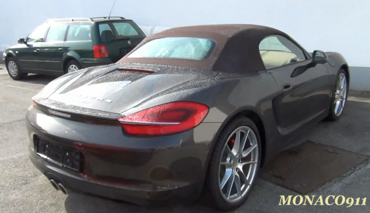 A car is parked next to a parking meter - Pistonheads - The image shows a black sports car with a retractable hard top in a parking lot during daylight. There is another vehicle, a green station wagon, parked behind it. The car features distinctive red taillights, silver rims, and a notable badge on the trunk. The hardtop roof is closed, and the vehicle appears to be in good condition, with no visible damage or dirt.