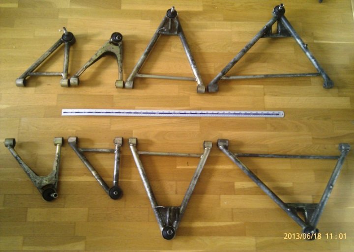 Little ordinary trauma, usually simple. - Page 1 - Elise/Exige/Europa/340R - PistonHeads - The image displays a collection of triangle-shaped metal rods arranged on a wooden floor. These rods are interconnected to form a larger structure, resembling the letters A, M, A, and I in a mechanical manner. One of the rods is long and aligned horizontally, while the others are angled and connect these ends. The metal has a rough, textured appearance, indicating it may be fabricated or repurposed material. The wood beneath it has visible grain patterns, suggesting a natural or unfinished surface. The date stamp in the bottom right corner of the image shows "2013 06 18 11:01", indicating when the photo was taken.