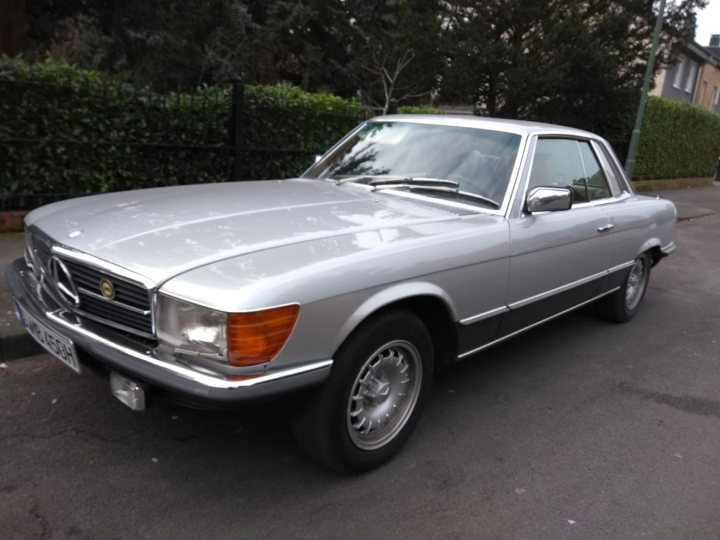 1973 Mercedes SLC - Page 10 - Readers' Cars - PistonHeads - The image displays a vintage Mercedes-Benz car parked on what appears to be a street. The vehicle is painted in a metallic gray color and features the distinctive grille and emblem associated with the Mercedes-Benz brand. The car appears to be well-maintained and its age is evident from its design and shape. Only the front half of the vehicle is visible in the image.