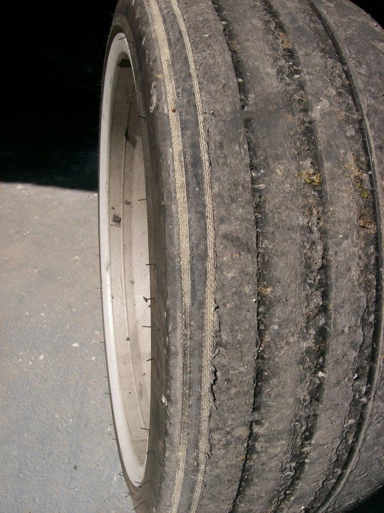 Wear Pistonheads Cups - The image displays the close-up view of a single wheel of a vehicle, specifically highlighting its tread and rim. The wheel appears to be a tire with a considerable amount of wear, as indicated by the heavily grooved tread and overgrown metal rims. The close-up perspective allows for a detailed look at these components, showcasing patterns of indentations and the material's condition.