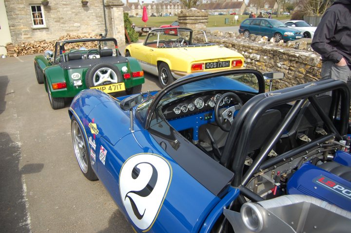 Northants pistonheads meet ? - Page 1 - Northamptonshire - PistonHeads - The image presents a scene of classic vintage cars parked outdoors. The cars, an antique blue and yellow consort, are parked in a row, emphasizing their uniformity. Each car has a unique number and license plate, indicating that they may be part of a club or competition. A group of men are standing next to the cars, looking at the show on display. The setting appears to be outside a building, suggesting that this could be a special event or a gathering for vintage car enthusiasts.