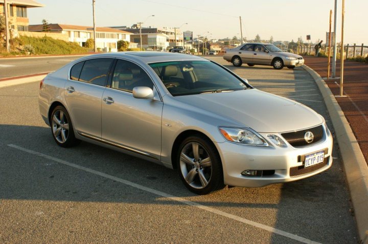 Pistonheads Phers Aussie - The image shows a gray sedan parked in a parking lot. The car appears to be a Lexus, indicated by the visible model and the distinctive grille design. The vehicle has a glossy finish and is prominently centered in the frame. In the background, there's a building and a car on the road, suggesting this is a public area with some parking available. The parking lot is adjacent to a street, and the cars and building suggest an urban setting.