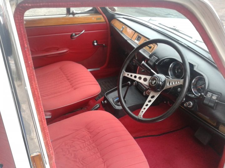 A close up of a luggage bag on a car - Pistonheads - The image features the interior of a classic car, dominated by red seats and a contrasting black steering wheel. The car's interior showcases a vintage style with chrome accents, including the wheel,likely made from metal with visible bolts. The red carpet and wooden paneling add to the classic ambiance. The interior is compact, indicative of an older or smaller vehicle design.