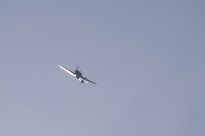 Camera Damn Fault Pistonheads - This image shows a vintage fighter plane flying across a clear blue sky. The plane is at an angle, suggesting it may be in the process of taking off or banking. The aircraft is small and has a pointed nose and a rounded tail, characteristic of older aviation designs. Given the clear sky and the plane's path, it might be involved in an air show or pilot training exercise. There is no visible text or branding within the image.