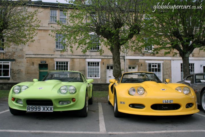 Sunday April 25th Bradford on Avon - Marocs - Page 1 - South West - PistonHeads - The image displays two vintage sports cars parked side by side in a parking lot adjacent to a building with green shutters. The cars are a bright light green and a vibrant yellow, and they both feature a classic design with round headlights, a wide hood, and a small front window. The setting appears to be in a residential area with tree branches partially visible in the background. The image has a watermark with the text "GlobalSupersCars" indicating the source or branding related to the cars.