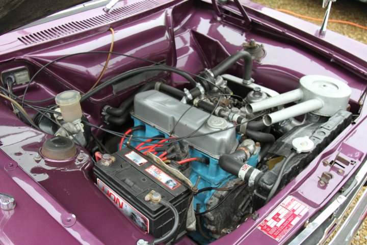 Hillman Avenger GLS Restoration - Page 1 - Readers' Cars - PistonHeads - The image presents a vibrant purple car engine showcasing the complexity of automotive mechanics. The engine, which appears to be an old-fashioned stock car model, is comprised of a multitude of parts and components. A prominent light-colored feature draws immediate attention - the alternator, an essential part of the car's electrical system. Surrounding this alternator are various wires and hoses, representing the intricate network of tubing and electrical connections within the engine. The backdrop of the image appears to be a driveway, suggesting a domestic or hobbyist setting, perhaps a garage or workshop where such automotive work is undertaken.