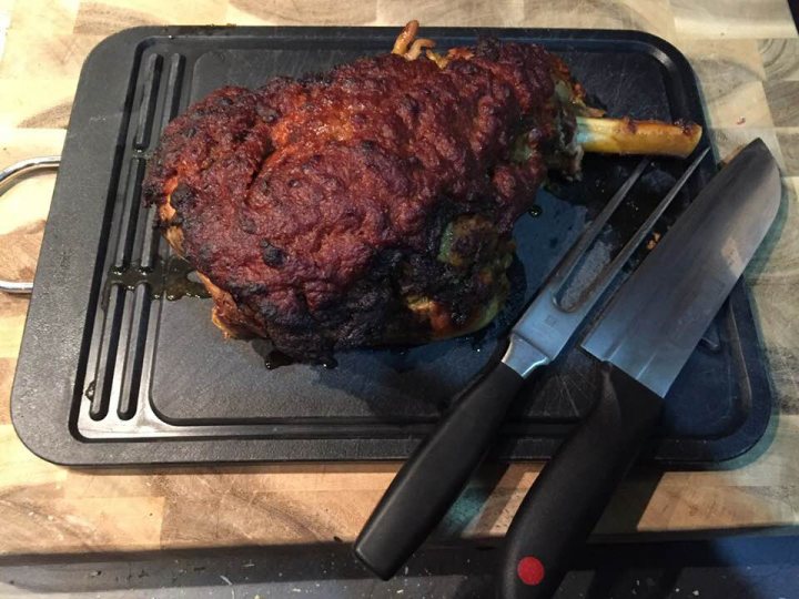 Photo of your dinner (vol 2) - Page 462 - Food, Drink & Restaurants - PistonHeads - The image shows a whole meal on a wooden table. There's a large piece of meat that appears to be grilled, occupying a significant portion of the image. The meat is displayed on a black cutting board. Beside it, on the same table, sit a knife and a tong. The knife and tong are flat, suggesting that they could be designed for use with food. The meat has some char marks, indicating it has been cooked, and the background is blurred, making it difficult to discern specific details.