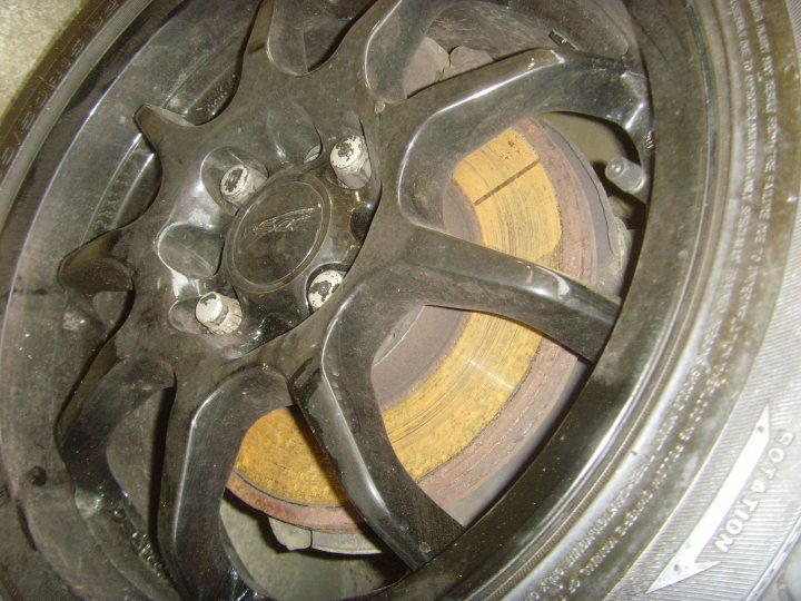 Pistonheads - The image features a close-up view of a car tire. The tire is black with a thick tread and a silver hubcap on the center. The hubcap has a spoke-like design and is made of metal, which stands out against the black rubber of the tire. One can see the rim of the tire, contributing to the overall view of the wheel. The tire itself appears to be in good condition, with no visible damage or wear.