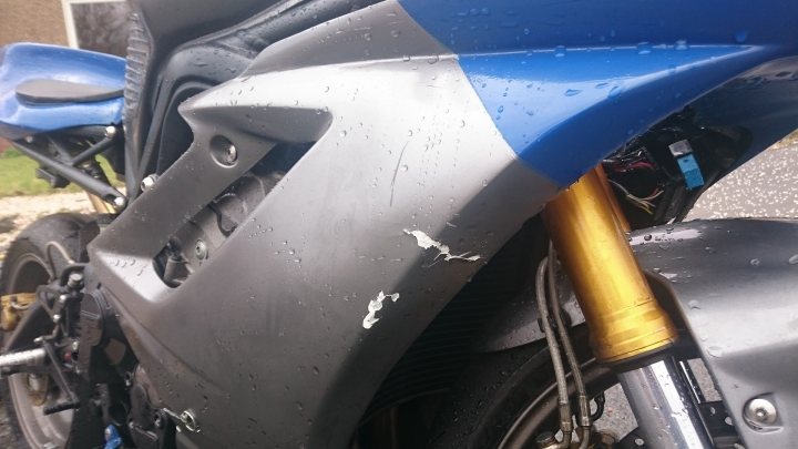 the bb trackday thread.   - Page 30 - Biker Banter - PistonHeads - The image displays a close-up view of the side of a motorcycle. The motorcycle has a color scheme of blue, black, and yellow, with the primary color being blue. There is visible damage on the side of the motorcycle, suggesting it may have had an accident or been involved in a fall. A yellow component is prominently visible at the bottom of the image, possibly a part of the motorcycle's exhaust system. The overall scene conveys a sense of wear and perhaps rough usage.