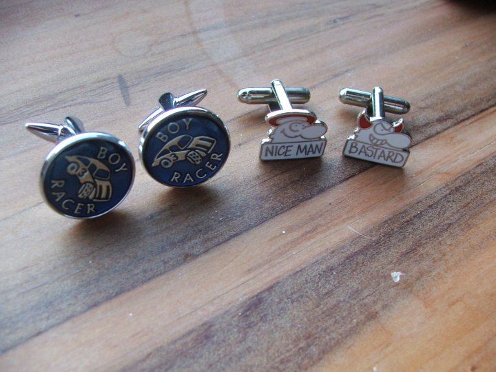 Pistonheads Cufflinks Todays - The image showcases a set of four unique cufflinks. Each cufflink features a silver neck, attached to which is a small silver ball featuring a printed message. The balls are made of different materials: two appear to be wood, one is metal, and the other is bone. Each ball carries a printed message - "BOY ROACER", "NICE MAN", "BASTARD". The cufflinks are arranged on a wooden surface, possibly a floor, with each one placed on its own.