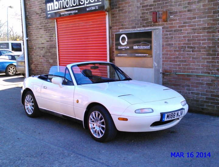 Pistonheads - The image depicts a white Mazda Miata sports car parked outdoors in front of a brick building. To the left of the car, there is an entrance, suggesting that the parking area might be attached to the building. On the left side of the brick building, there's a banner with the website address "www.mbmotorsport.co.uk," and on the right, another section of the building has the text "Motorsport Limited." In the background, there are other vehicles visible, indicating that this might be a commercial or public parking area. The watermark on the image says "MAR 16 2014," suggesting that the photo may have been taken in or around March 2014.