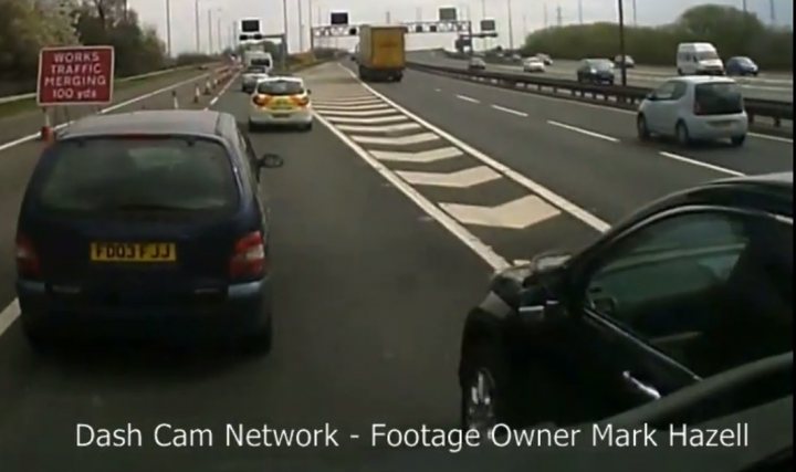 HGV vs caravan smash on the M6 - Page 17 - General Gassing - PistonHeads - The image depicts a multi-lane highway, bustling with vehicle traffic. A green and white striped pedestrian crossing is clearly visible on the left side of the road, adjacent to a sign that reads "Work Merge 100 Yds." There are various types of vehicles, including cars and trucks, encountered at different distances and positions on the road. The cars' rear bumpers show multiple license plates. In the lower right corner of the image, a text label identifies the source of the footage as "Dash Cam Network - Footage Owner Mark Hazell."