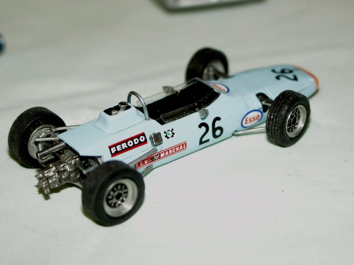 Collection Pistonheads - This is a side view of a die-cast model car. The car has visible brand logos on the side including FERRADO and Esses. It has the number 26 prominently displayed. The model car is oranish-blue in color. The car is positioned on a white surface and it appears to have four wheels.