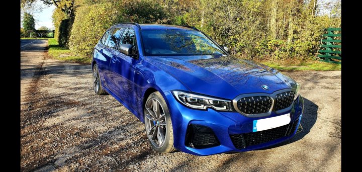 M340i - Page 49 - BMW General - PistonHeads - The image shows a blue BMW car parked on what appears to be a gravel surface. The car is positioned at an angle and is facing towards the left side of the frame. It has a distinctive design with a prominent kidney grille, angular headlights, and a sporty stance. In the background, there's a grassy area and a tree, indicating a rural or suburban setting. There are no visible people in the image.