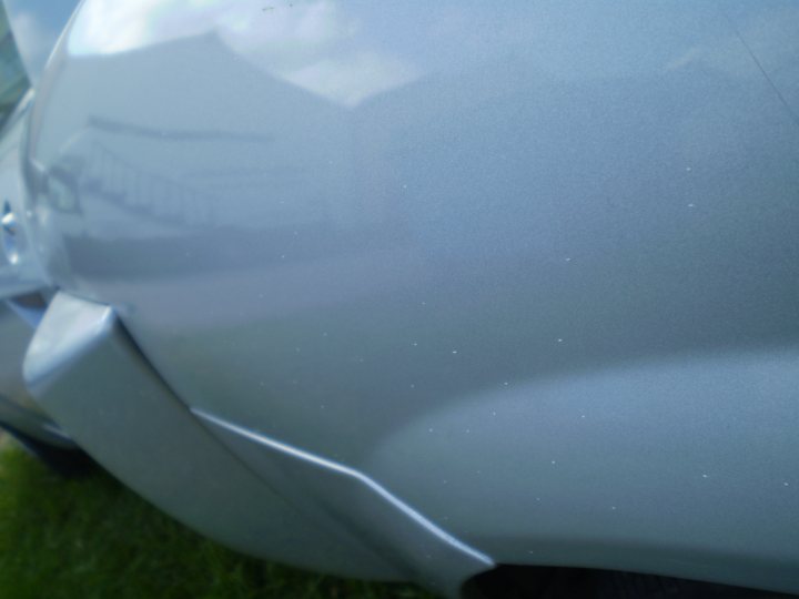 Work Job Managed Pistonheads Paint Give Painters - The image captures a close-up view of the back of a car, highlighting its metallic surface. The car appears to be parked on a green lawn. The area around the car's tail light includes a reflection, suggesting that the photo was taken outdoors.