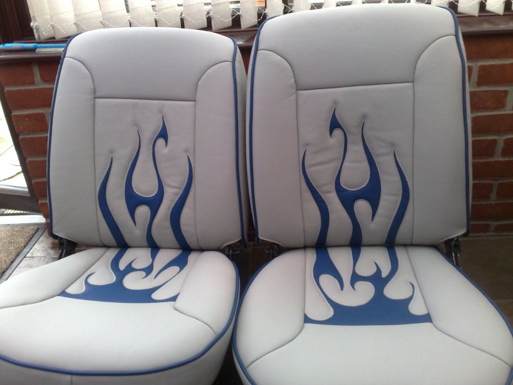 Truck Chevy Pistonheads - The image features a couple of white upholstered chairs with blue flame designs. One chair is positioned fully, while the other chair is shown from one side, specifically the backrest area. Both chairs have a round design visible from the back. The chairs are situated next to a brick wall with white-framed blinds. The design of the flames adds a touch of creativity and novelty to the otherwise simple furniture pieces.