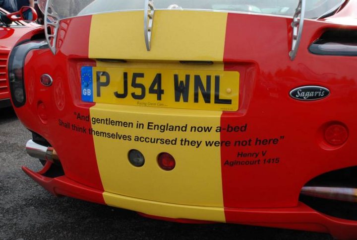 Pistonheads Sunday Supercar - The image shows the rear end of a brightly colored car with a striking design. The back of the car is yellow and red, making it highly noticeable. On the top of the back windshield, there's a unique charm that says 'And gentlemanmen in England now a-bed/Shall think themselves accursed they were not here.' On the license plate, the text 'P J54 WNL' is visible. This bold statement adds a personal touch to the vehicle, making it unique and memorable.