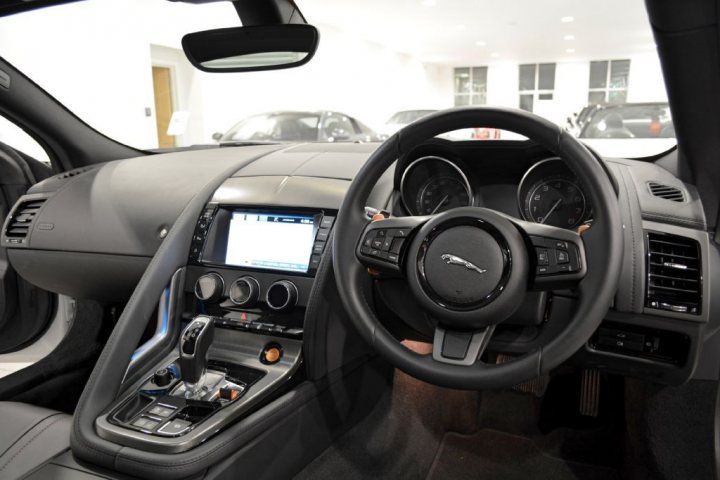 I've just bought an F-Type (pictures) - Page 1 - Jaguar - PistonHeads - This image shows an interior view of a luxury car dashboard, viewed through the front seat. The dashboard is adorned with a mix of silver and dark colors, and features a digital infotainment system, multiple air vents, passenger windows, door handles, and steering wheel controls, including a key labeled 'Sat Burner' and a button identified as 'Panoramic Roof'. The layout suggests a modern and comfortable driving experience, with a focus on convenience and luxury.